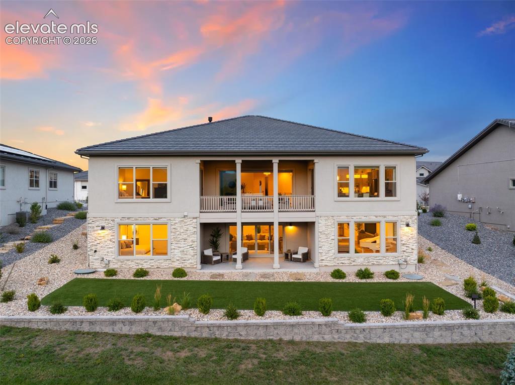 Image 45 of 50: Stucco exterior with stone accents, a covered balcony, and a covered patio