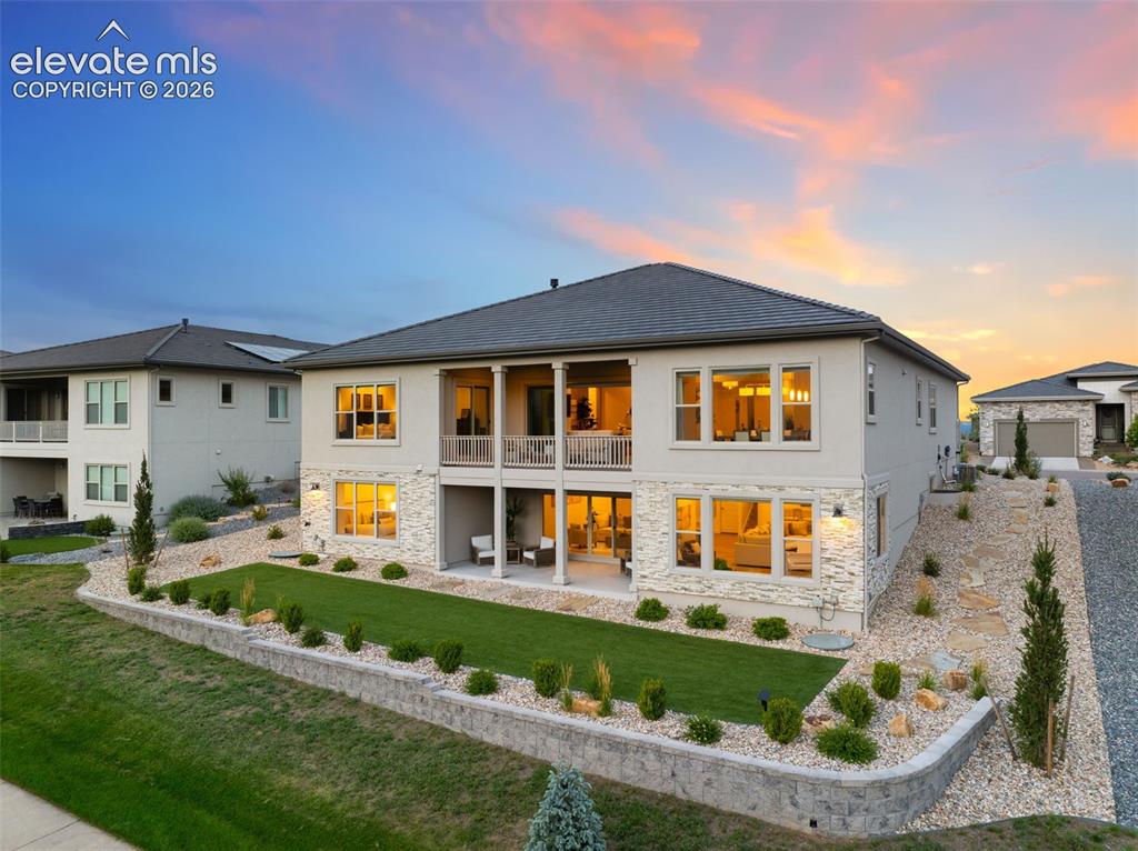 Image 46 of 50: Stucco exterior with stone accents, a covered balcony, and a covered patio.