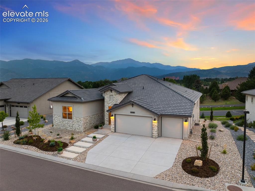 Image 5 of 50: Contemporary exterior with a tile roof, stone and stucco facade, and an att