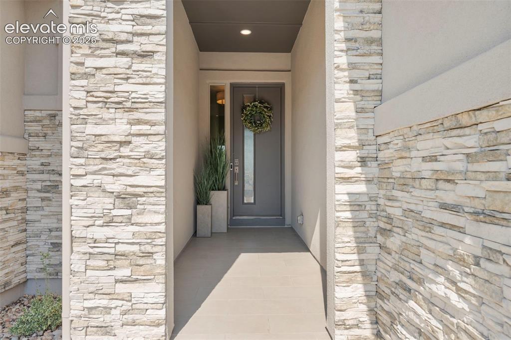 Image 6 of 50: Stacked stone veneer columns frame the entry, featuring a recessed entryway