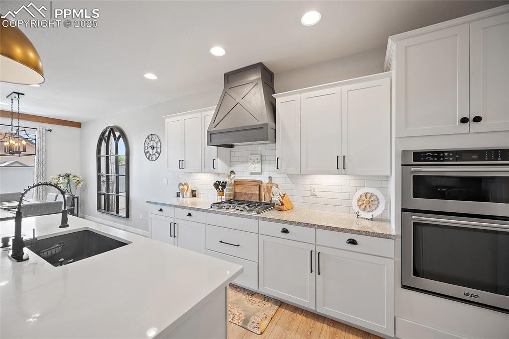 Image 10 of 41: Kitchen with stainless steel appliances, premium range hood, white cabinets
