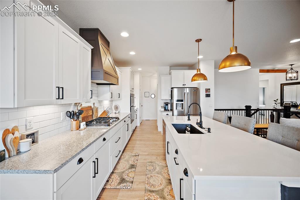 Image 8 of 41: Kitchen with stainless steel appliances, premium range hood, light wood-typ