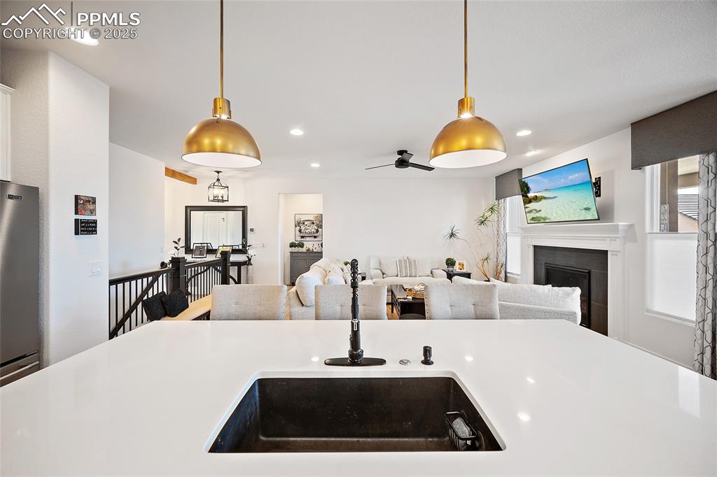 Image 9 of 41: Kitchen with light countertops, a tile fireplace, hanging light fixtures, r