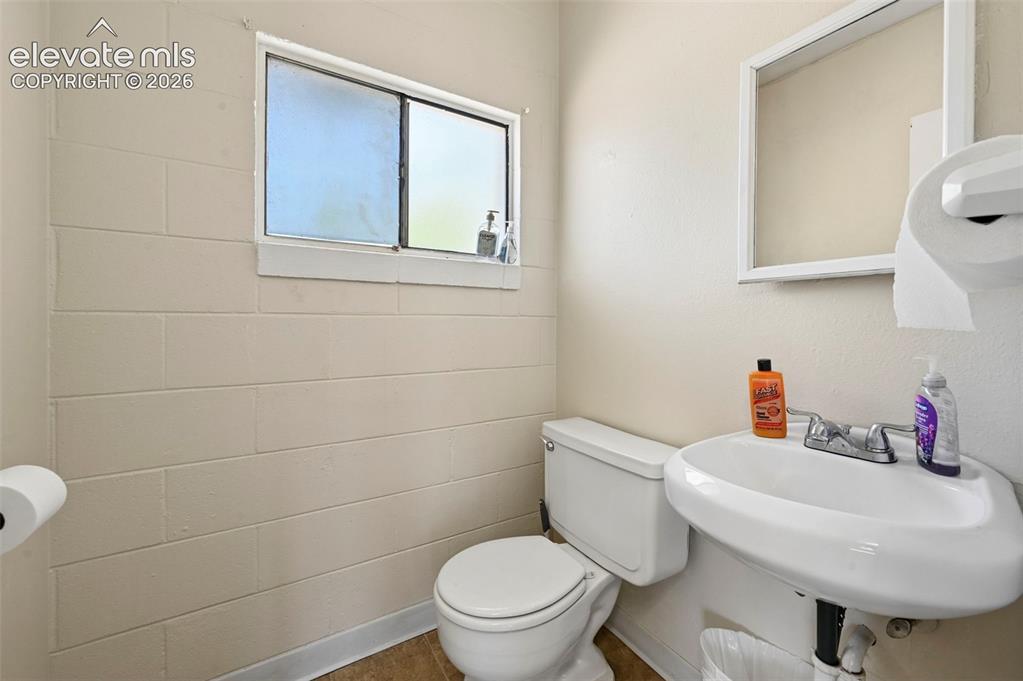 Image 12 of 23: Pedestal sink, wall-mounted mirror, and wood-finish flooring