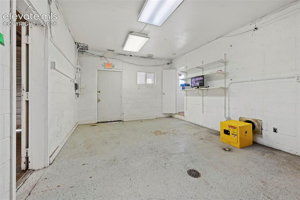 Image 15 of 23: Expansive utility room featuring concrete block walls, overhead fluorescent
