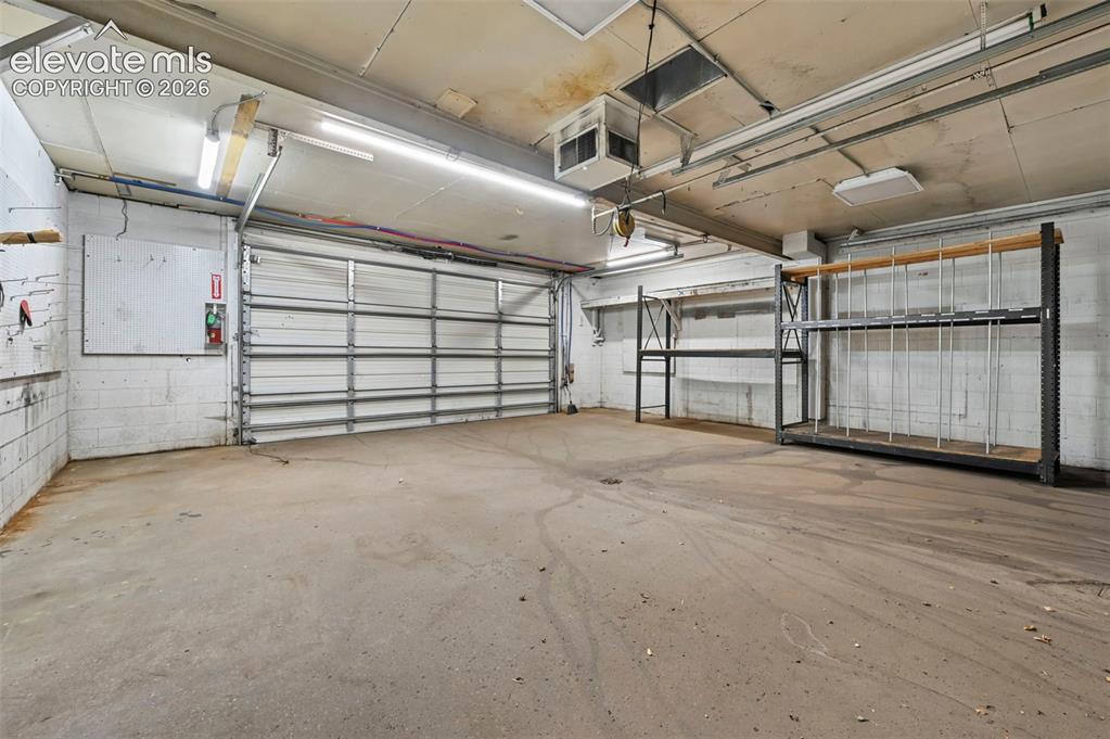 Image 19 of 23: Concrete flooring, fluorescent lighting, exposed ceiling conduit, metal rol