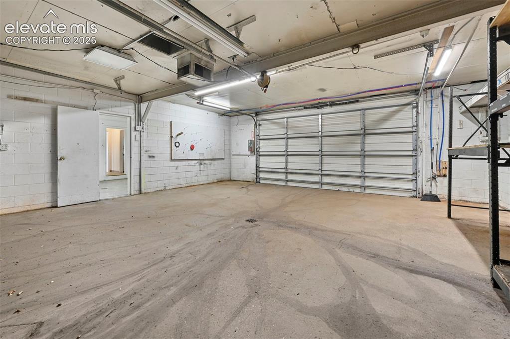 Image 20 of 23: Garage featuring a concrete floor, white block walls, and an overhead roll-