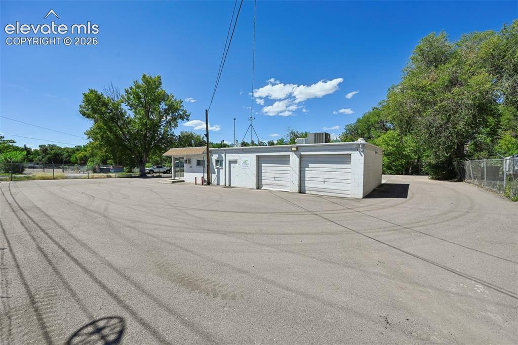 Image 3 of 23: Expansive paved lot with two attached garage bays