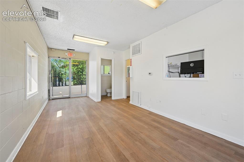 Image 6 of 23: Wood-finish flooring, white painted walls, and glass double doors