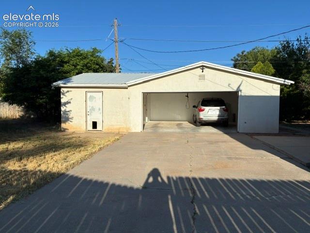 Image 3 of 19: Two-car garage with stucco exterior and metal roof