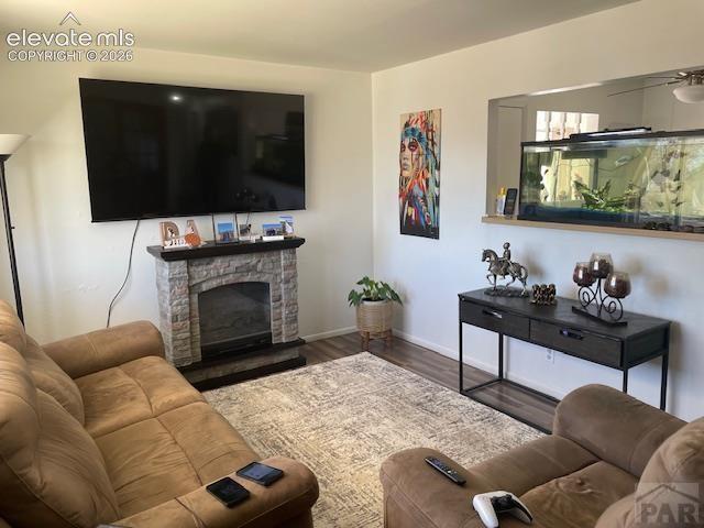Image 5 of 19: Living area featuring wood-finish flooring and a stone-clad fireplace
