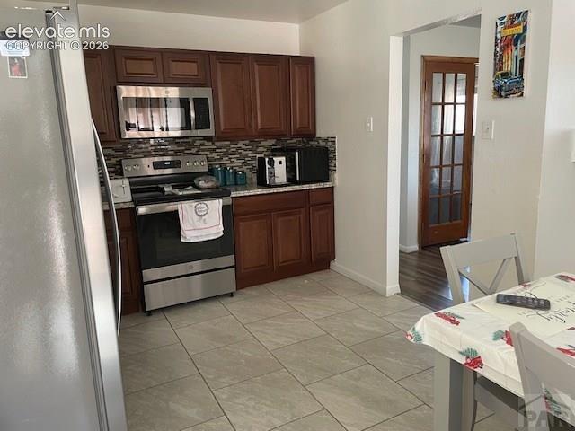 Image 6 of 19: Kitchen featuring tile flooring, dark wood cabinetry, stainless steel appli