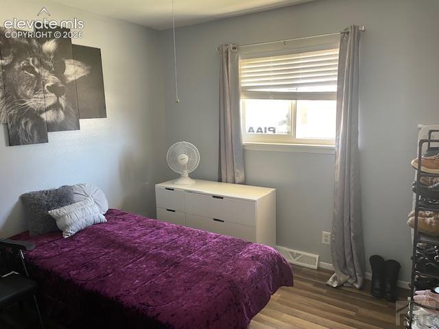 Image 9 of 19: Interior room featuring wood-finish flooring, a single window with blinds,