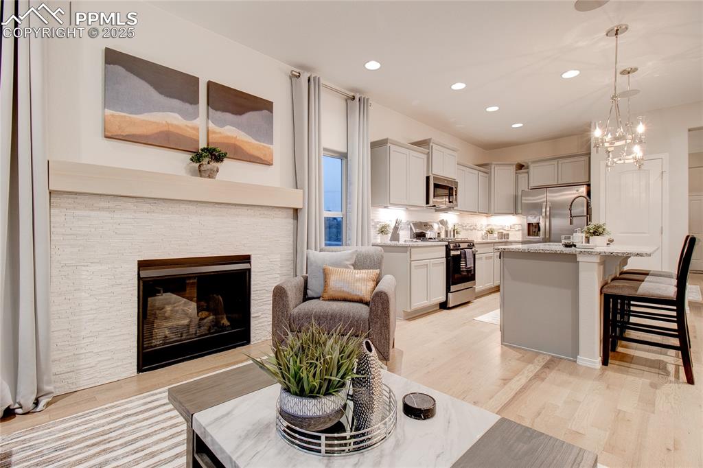 Image 11 of 28: Living room featuring light wood-type flooring, recessed lighting, a stone 