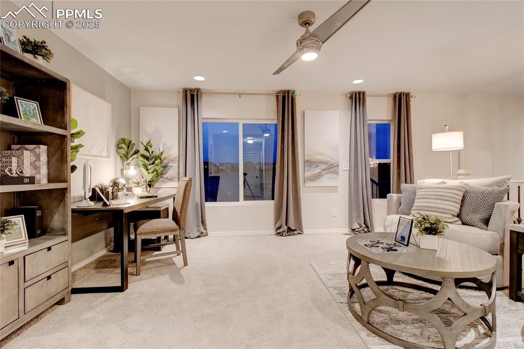 Image 18 of 28: Living area with light colored carpet, recessed lighting, and a ceiling fan