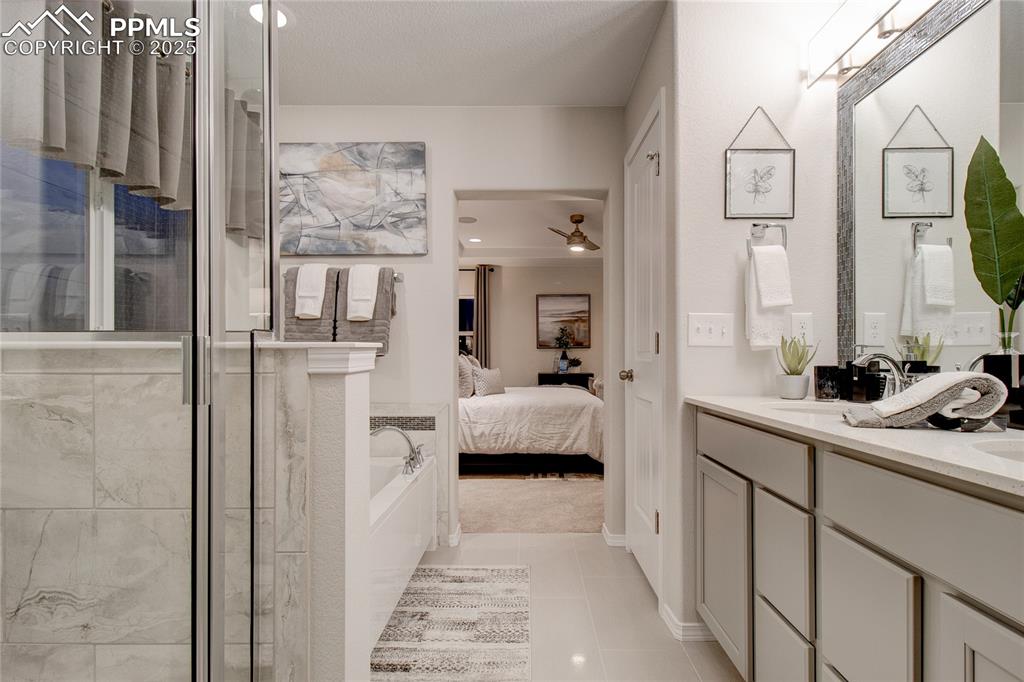 Image 21 of 28: Ensuite bathroom with double vanity, light tile patterned floors, a shower 
