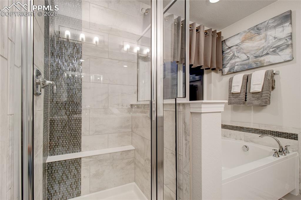Image 23 of 28: Bathroom with a shower stall and a bath