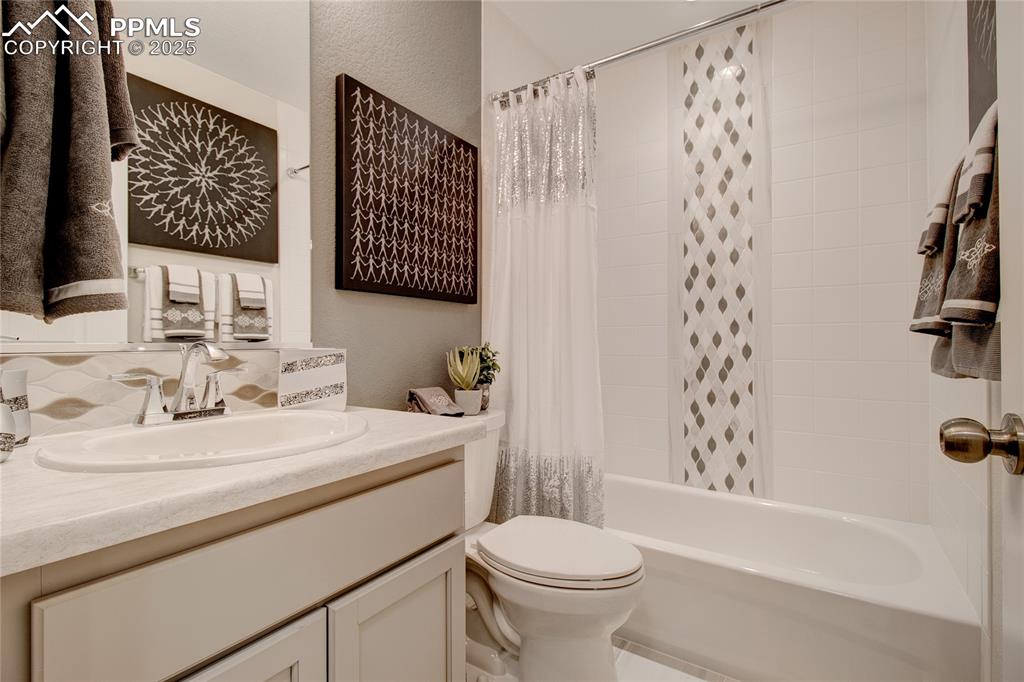 Image 24 of 28: Full bathroom with shower / bath combination with curtain, vanity, and a te
