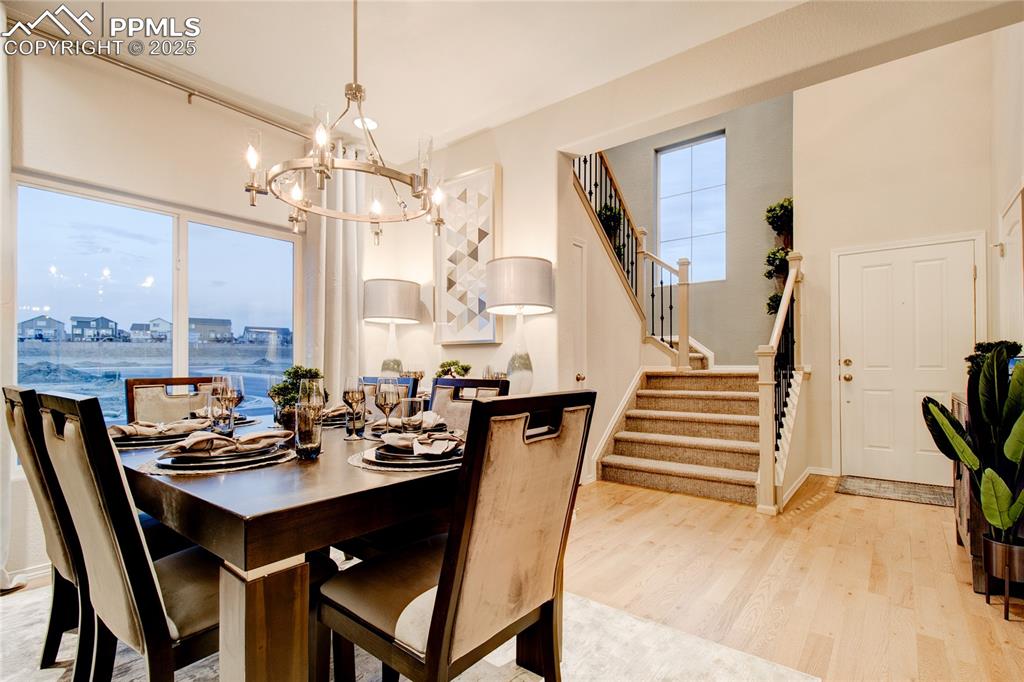 Image 6 of 28: Dining room with stairs, light wood-style flooring, and a chandelier