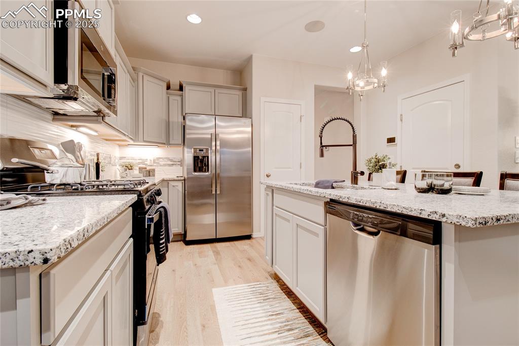 Image 8 of 28: Kitchen with stainless steel appliances, light wood finished floors, decora