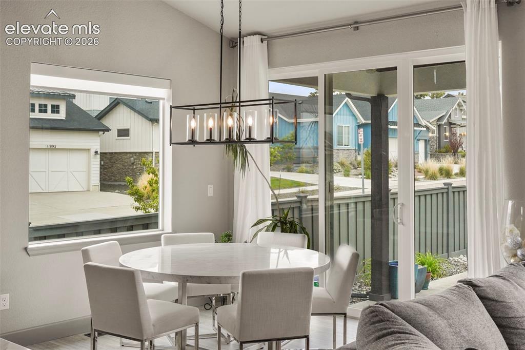 Image 13 of 31: Contemporary dining area featuring a linear chandelier, ample natural light