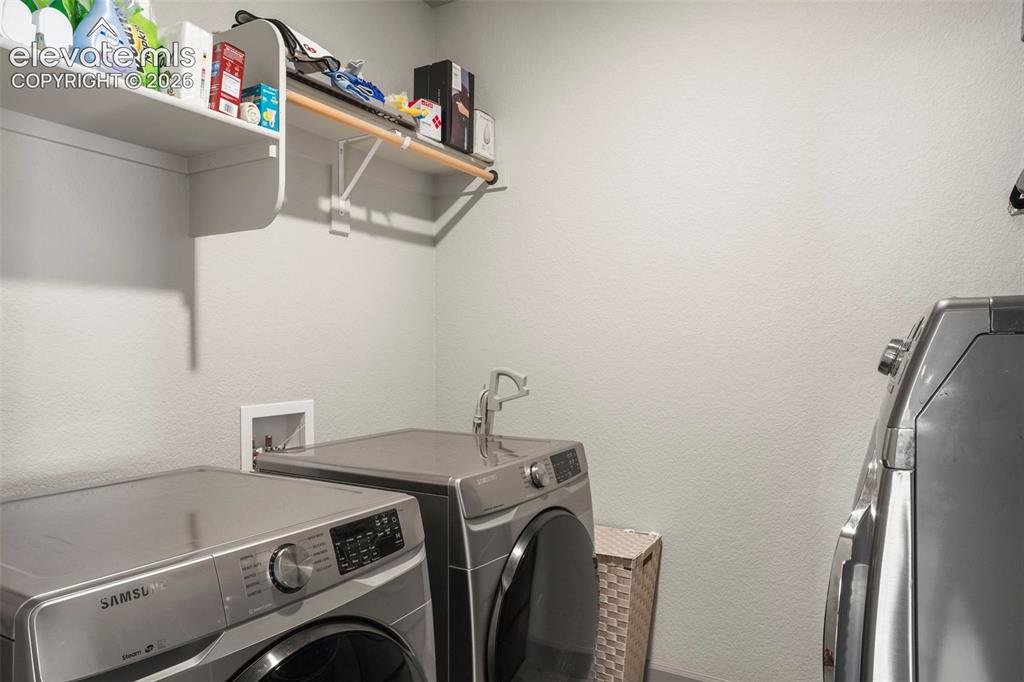 Image 15 of 31: Dedicated laundry area featuring light-toned walls and built-in shelving