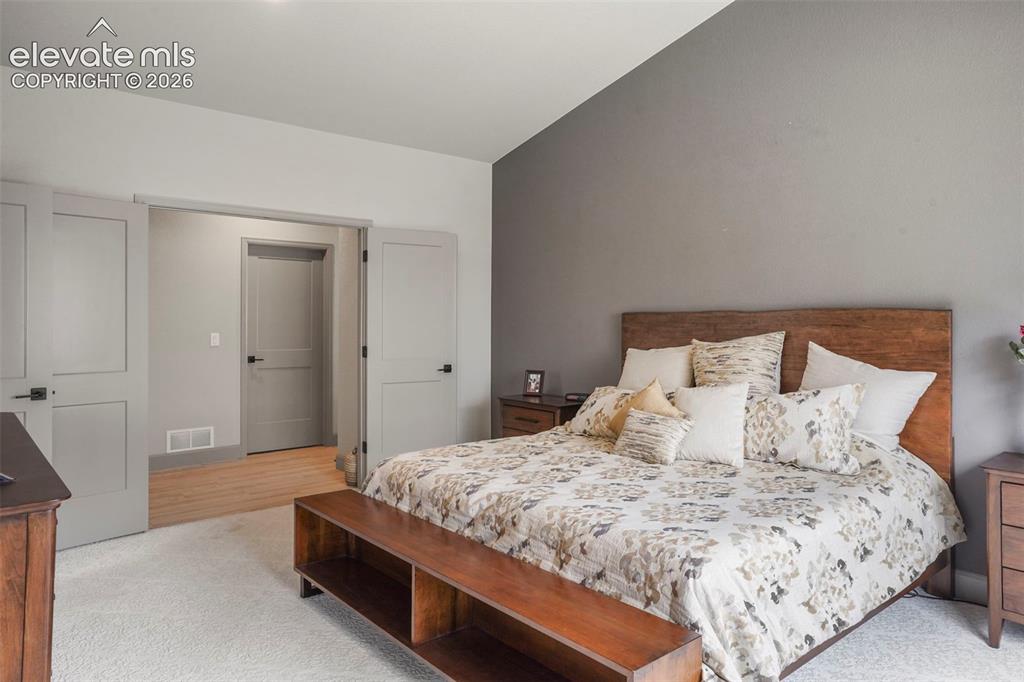 Image 17 of 31: Bedroom featuring a light grey accent wall, white textured carpet flooring,
