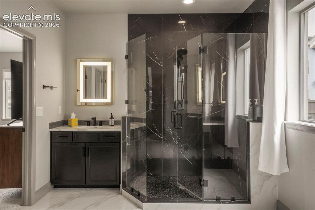 Image 19 of 31: Spacious bathroom featuring a glass-enclosed shower with dark marble-style