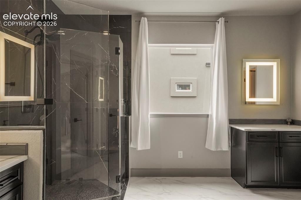 Image 20 of 31: Modern bathroom showcasing a spacious glass-enclosed shower with dark marbl