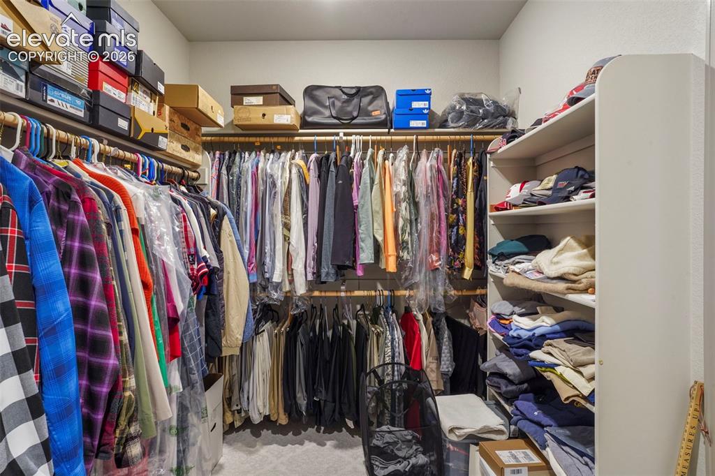 Image 21 of 31: Walk-in closet featuring extensive built-in shelving, multiple hanging rods