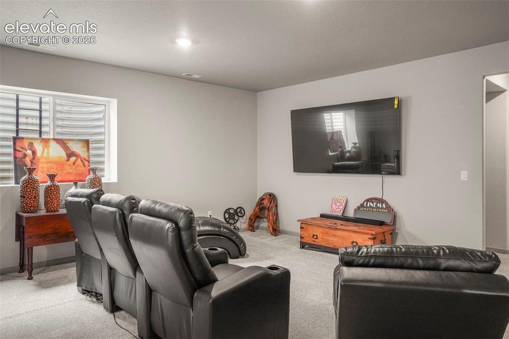 Image 24 of 31: Carpeted entertainment area featuring a wall-mounted display, recessed ceil