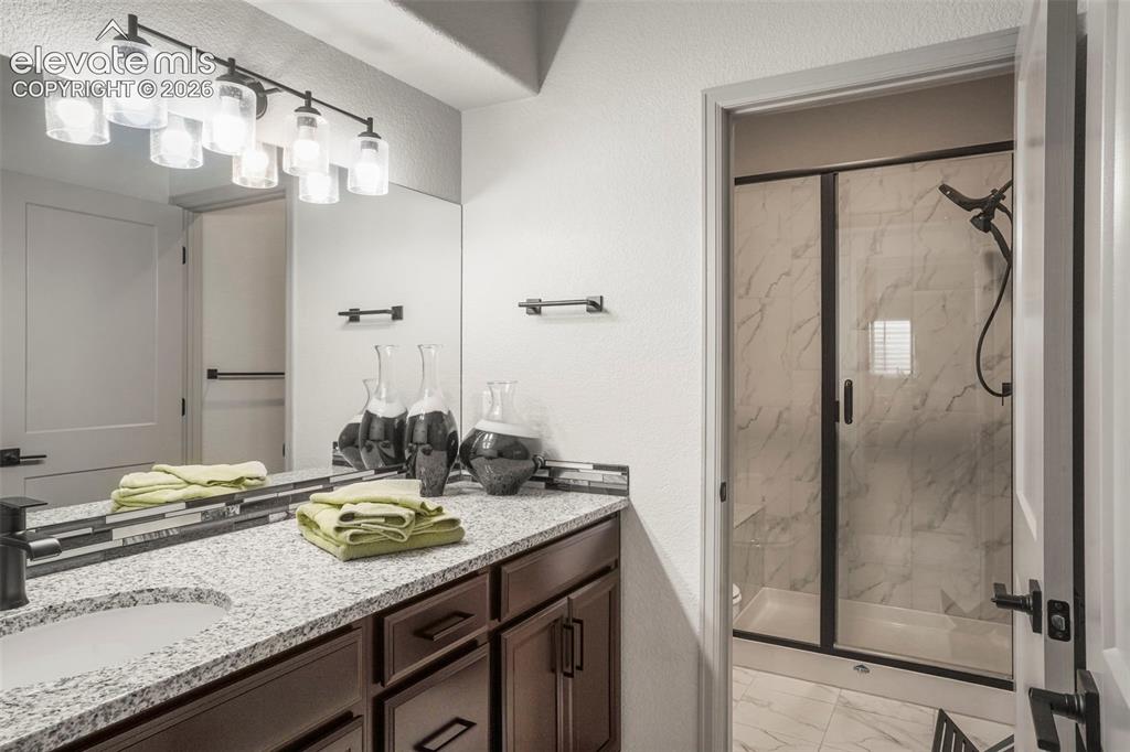 Image 27 of 31: Bathroom featuring a dual vanity with granite-finish countertops, dark wood