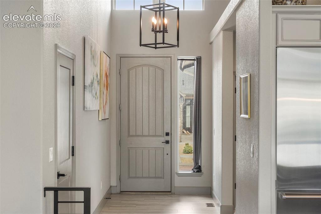 Image 3 of 31: Entryway featuring a light-toned wooden door with vertical paneling, a full