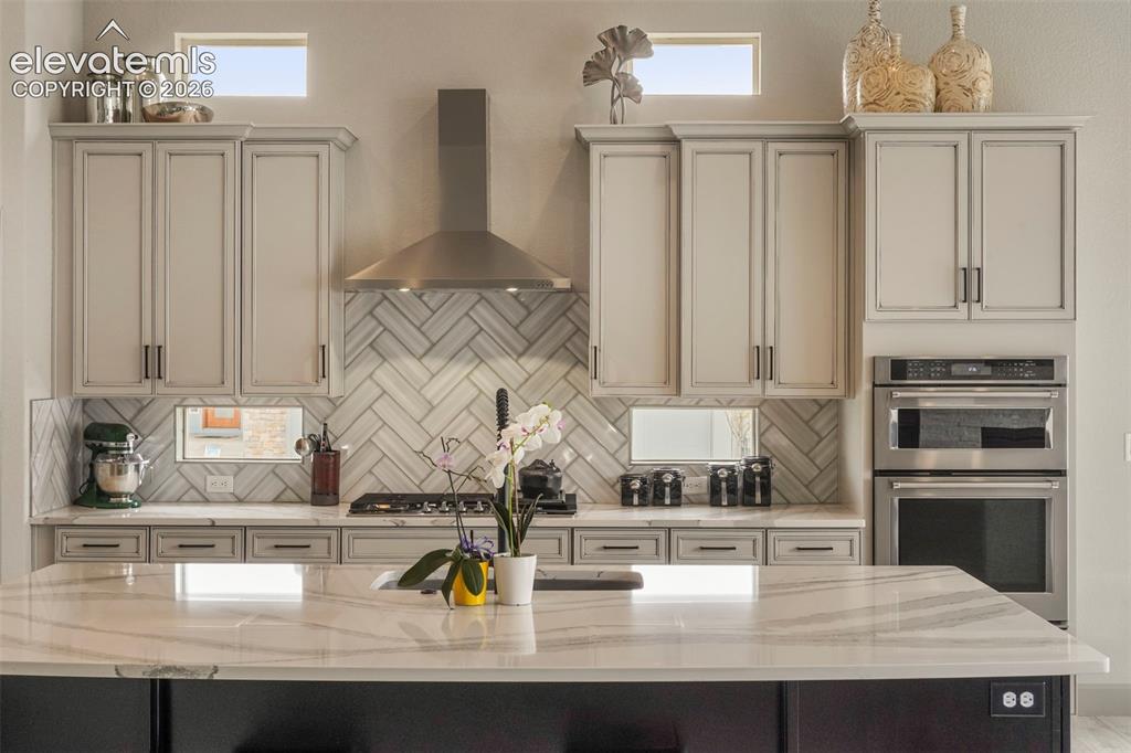 Image 8 of 31: Gourmet kitchen featuring a substantial island with a white countertop, lig