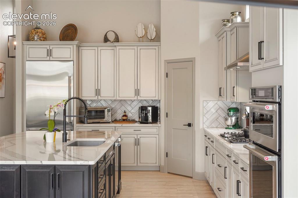 Image 9 of 31: Gourmet kitchen featuring a central island with an undermount sink, marble-