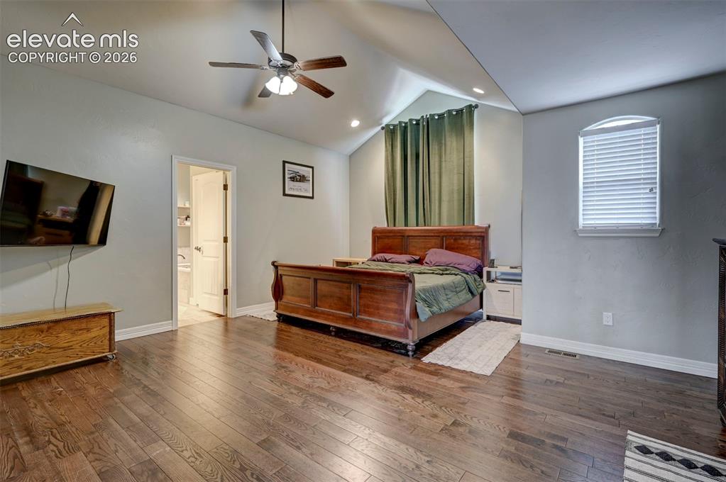 Image 25 of 49: Vaulted primary bedroom with hardwood floors
