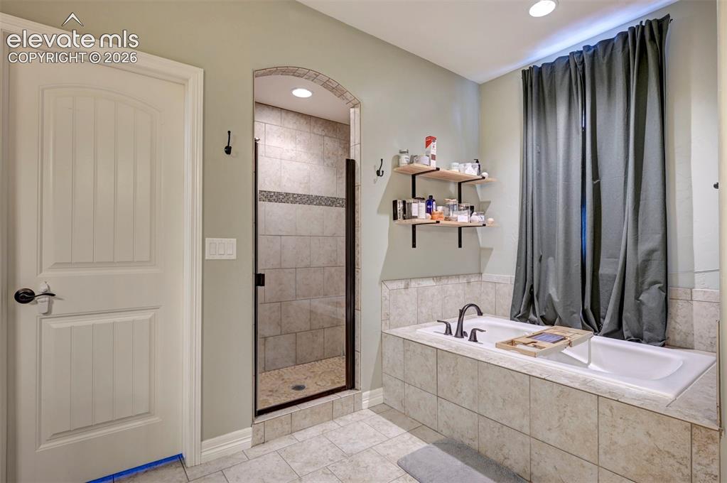 Image 35 of 49: Primary bath: jetted tub and tiled shower