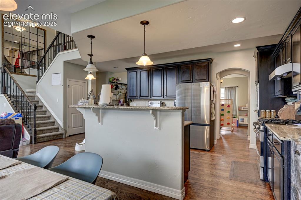 Image 9 of 49: Kitchen with granite counters, island with breakfast bar and dark cabinetry