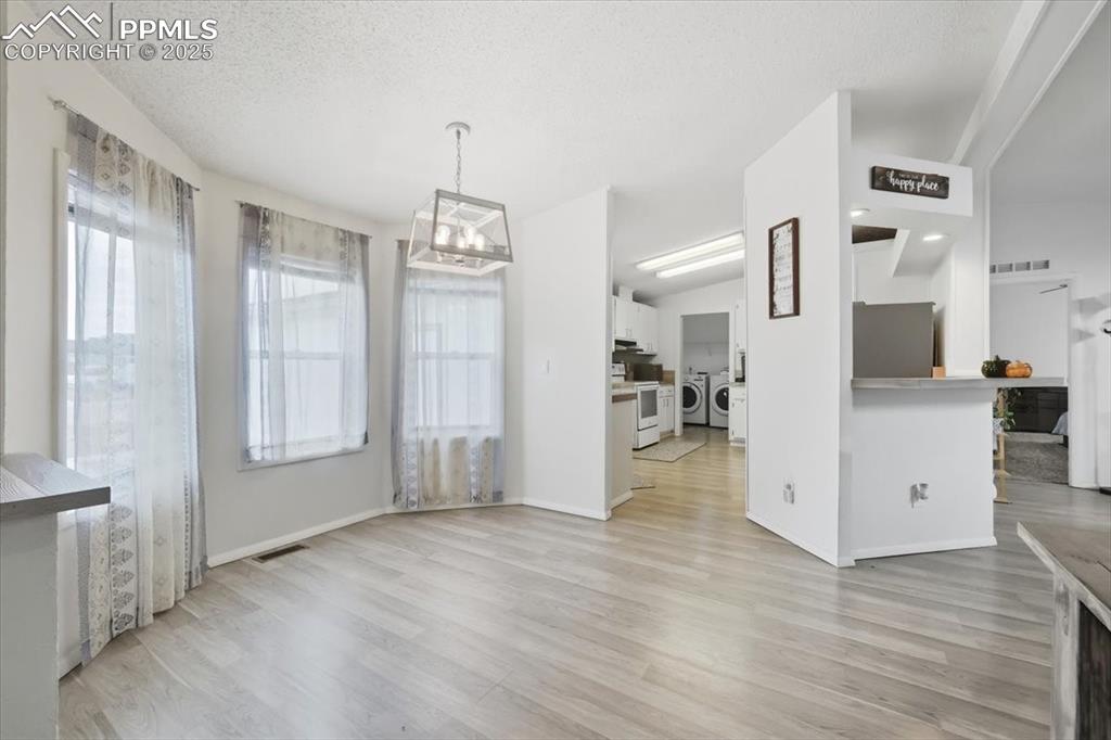 Image 10 of 45: Unfurnished dining area with light wood finished floors, washing machine an