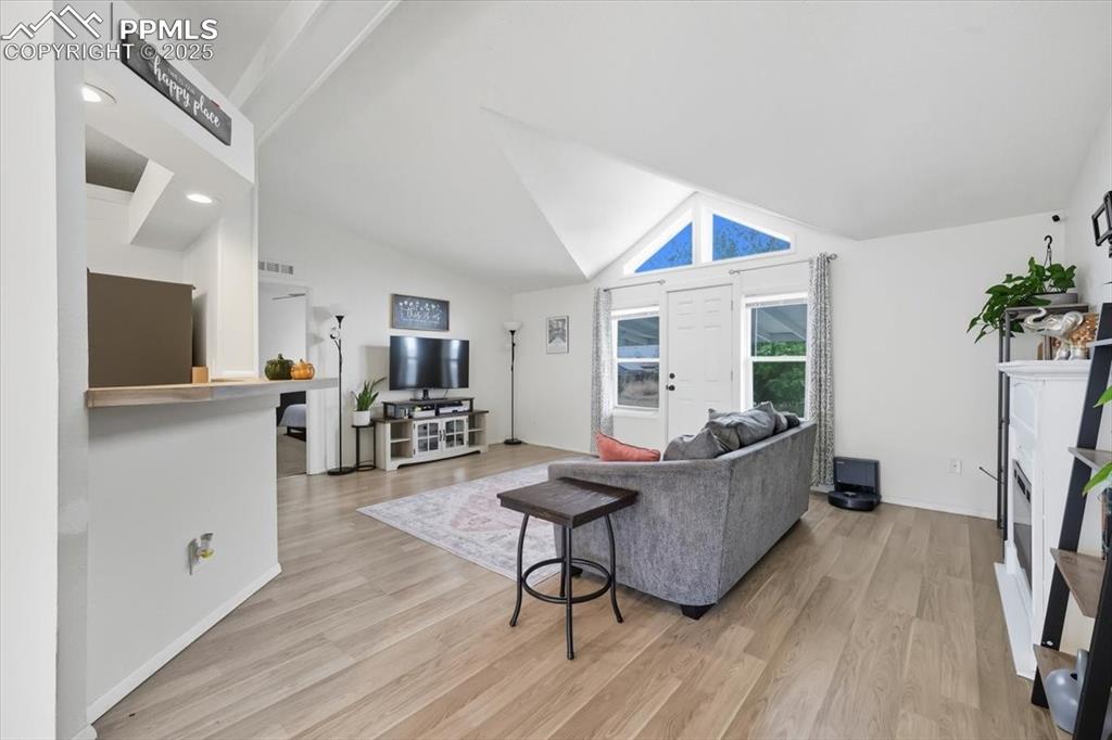 Image 11 of 45: Living room featuring light wood-type flooring and high vaulted ceiling