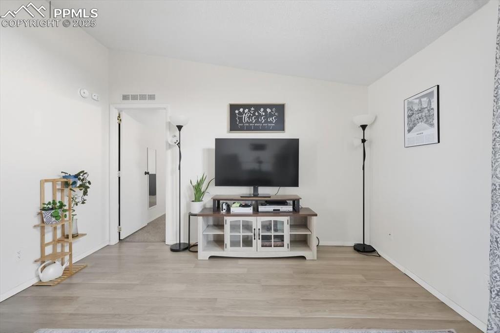 Image 14 of 45: Living area with vaulted ceiling and light wood-type flooring