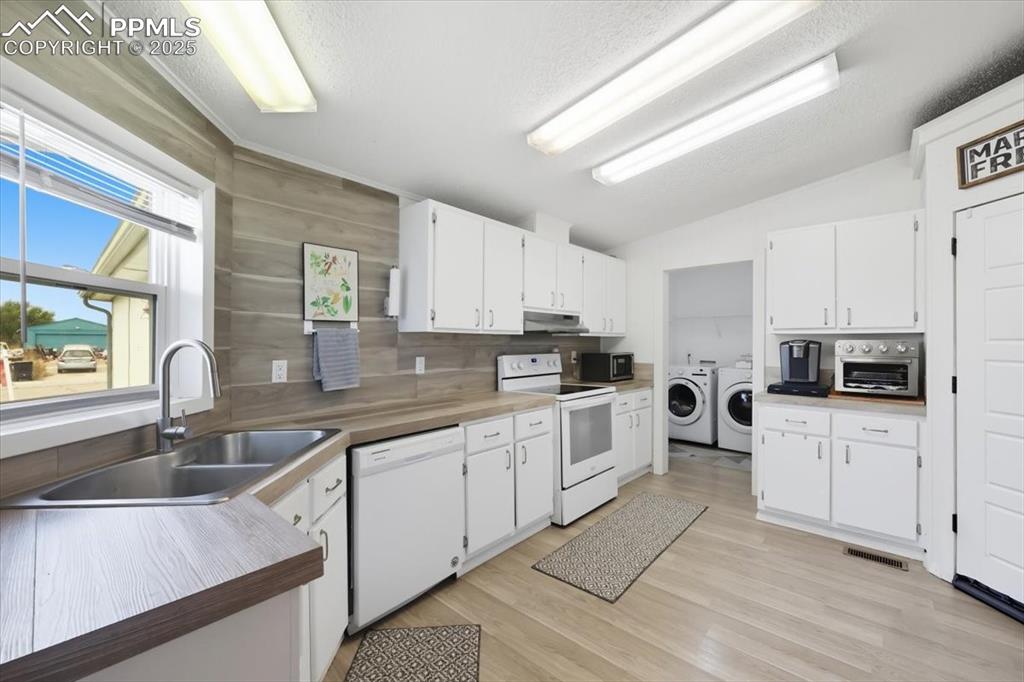 Image 17 of 45: Kitchen with washing machine and clothes dryer, white appliances, white cab