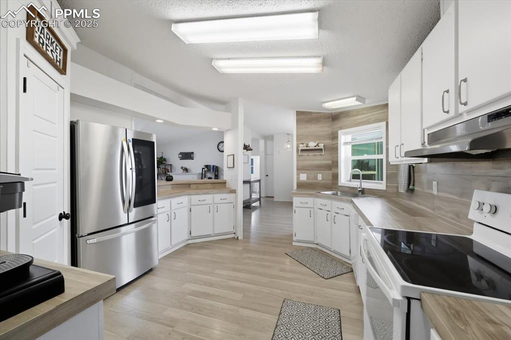 Image 18 of 45: Kitchen with white range with electric stovetop, smart refrigerator, white
