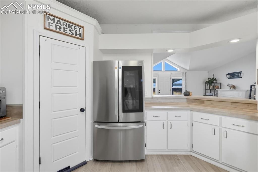 Image 19 of 45: Kitchen with freestanding refrigerator, white cabinetry, light wood-type fl