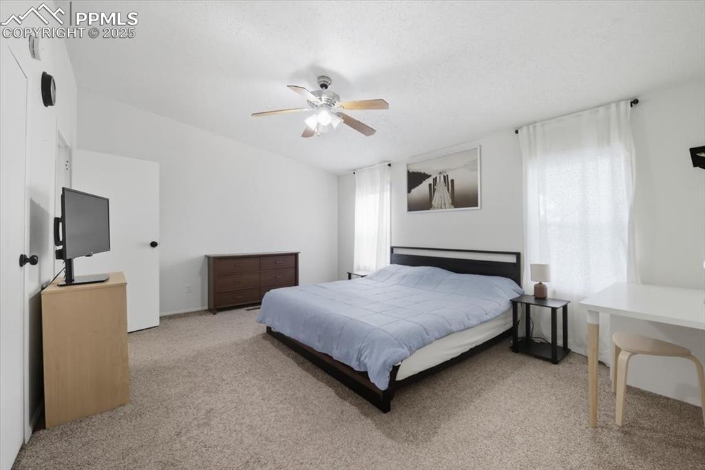 Image 22 of 45: Bedroom with light colored carpet and a ceiling fan
