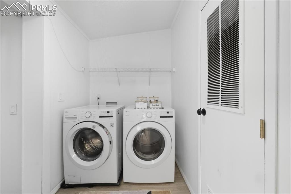 Image 32 of 45: Laundry area with light wood-style flooring and washer and clothes dryer
