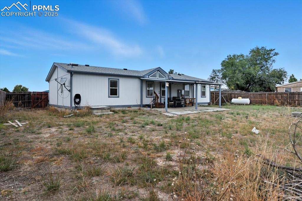 Image 39 of 45: Rear view of house with a fenced backyard and a patio area