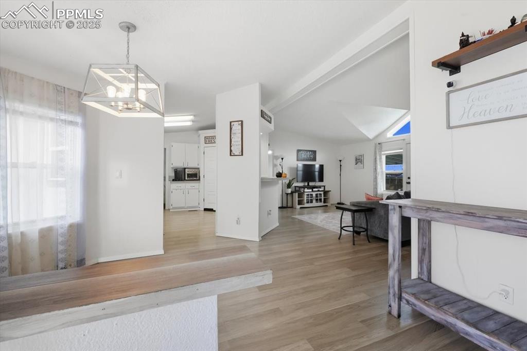 Image 7 of 45: Dining space with light wood-style floors, a chandelier, and vaulted ceilin
