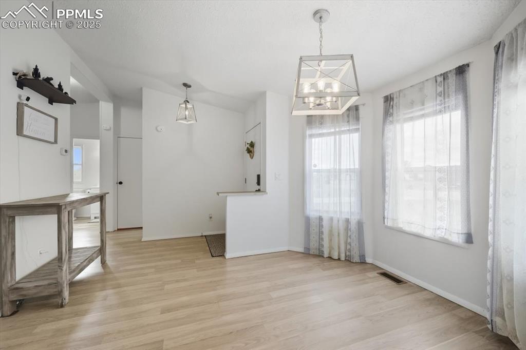 Image 8 of 45: Unfurnished dining area featuring light wood finished floors and a chandeli