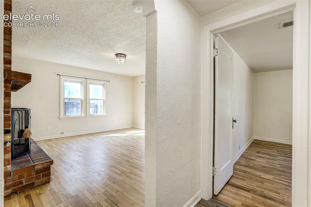 Image 11 of 50: Brick fireplace with a raised hearth, wood-finish flooring, and recessed ce